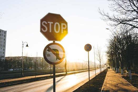 Empty urban street with stop and no U-turn signs under a warm sunset light.